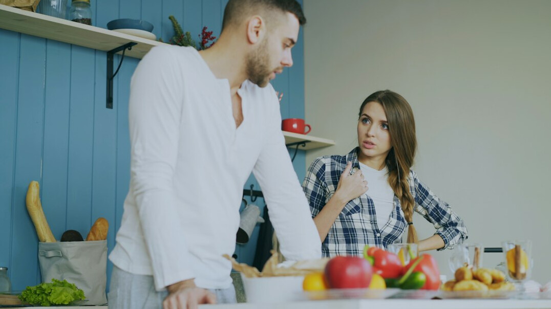 Latin American couple in their late fifties talking calmly about household expenses at a living room table