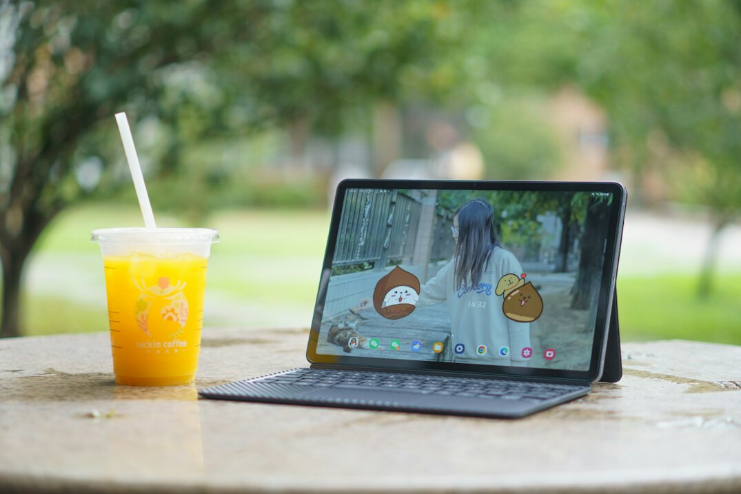 Laptop with a video call on a sunny table next to a cup of coffee and a notepad