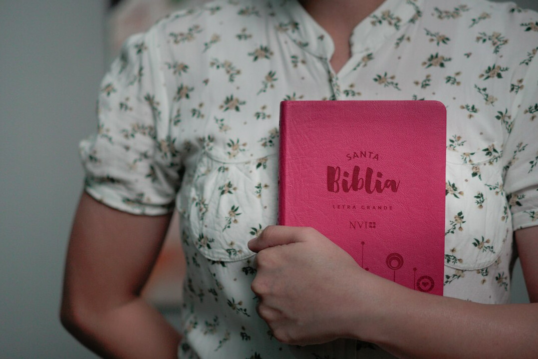 Young Latin American woman in her thirties with a ponytail smiling while holding a notebook